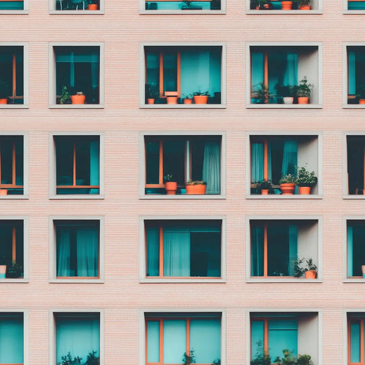 Nahaufnahme rosa Gebeudefassade mit quadratischen Fenstern und Topfpflanzen