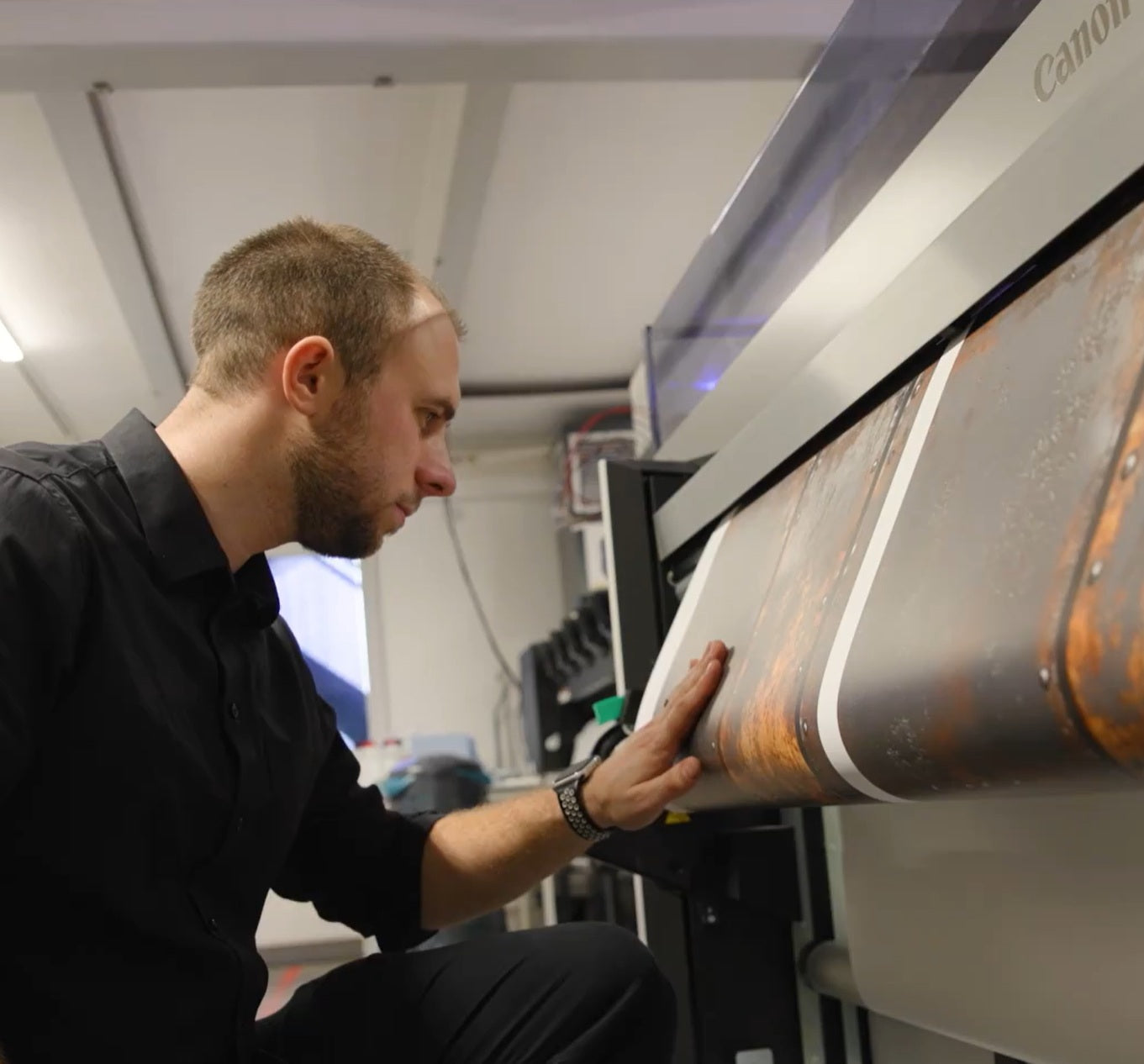 Mitarbeiter prüft Großformatdruck an einer Canon Druckmaschine in der Produktion, Kontrolle einer bedruckten Folie im Digitaldruckverfahren.