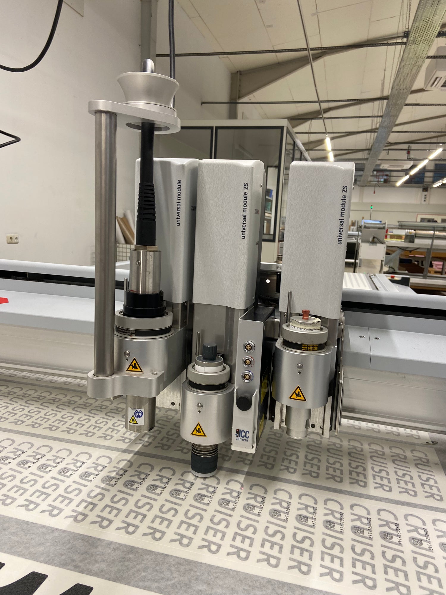 Werkzeugkopf eines Zünd G3 Schneideplotters beim präzisen Zuschnitt von Tapeten- oder Folienbahnen in der Produktion
