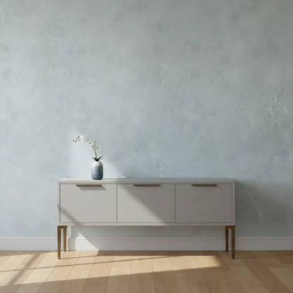 Selbstklebende Tapete Glatte Betonoptik – Heller Industrial Look an Wand hinter Sideboard im minimalistischen Wohnraum mit Holzfußboden.