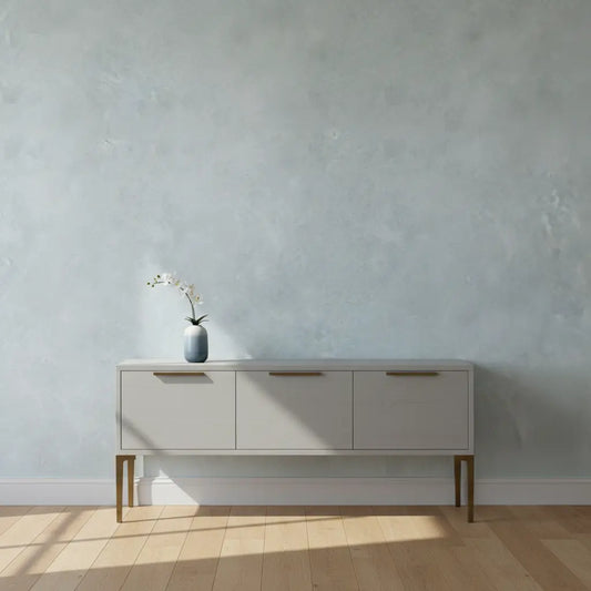Selbstklebende Tapete Glatte Betonoptik – Heller Industrial Look an Wand hinter Sideboard im minimalistischen Wohnraum mit Holzfußboden.